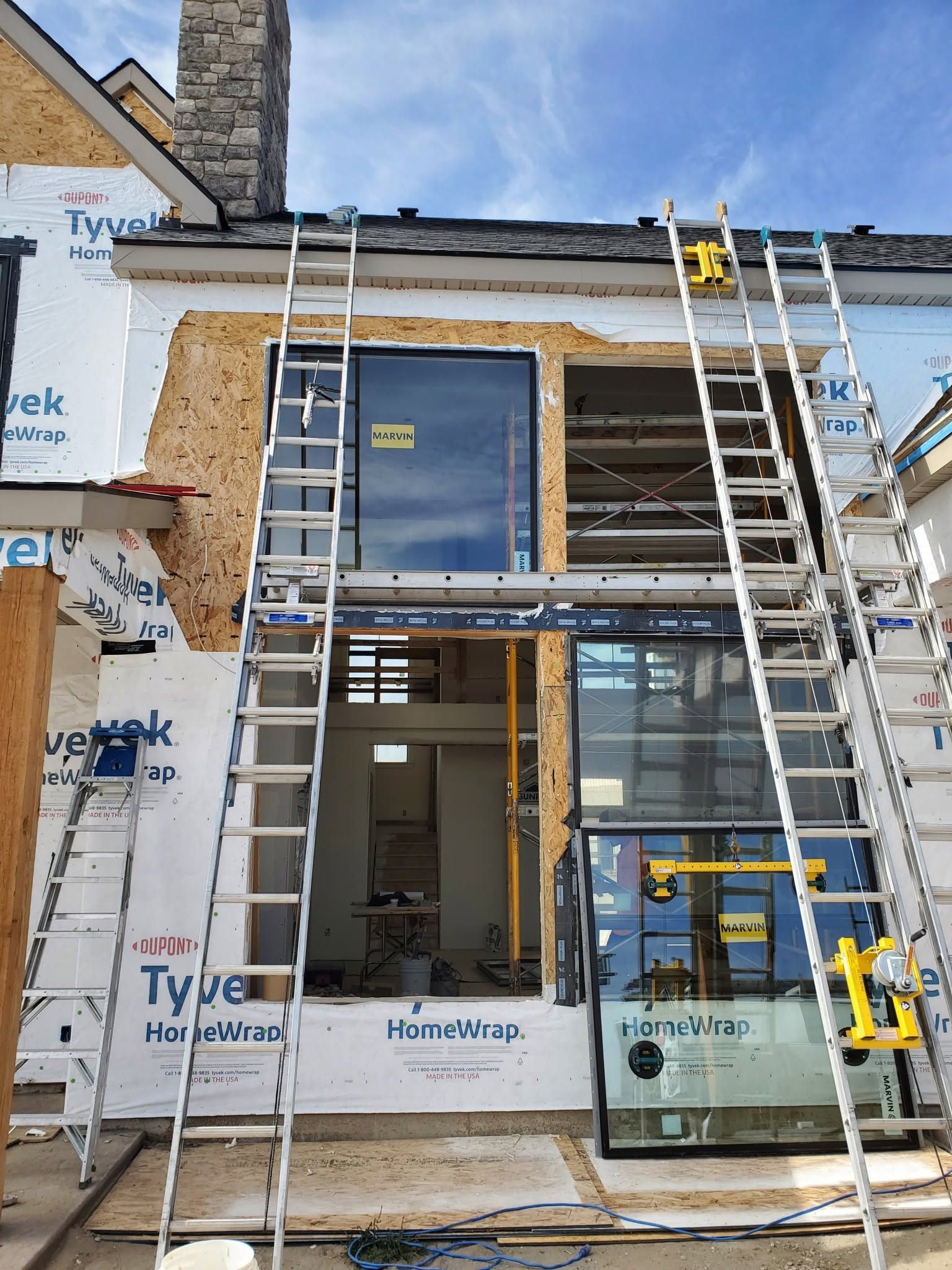 Partly built house exterior with ladders, scaffolding, and unfinished windows