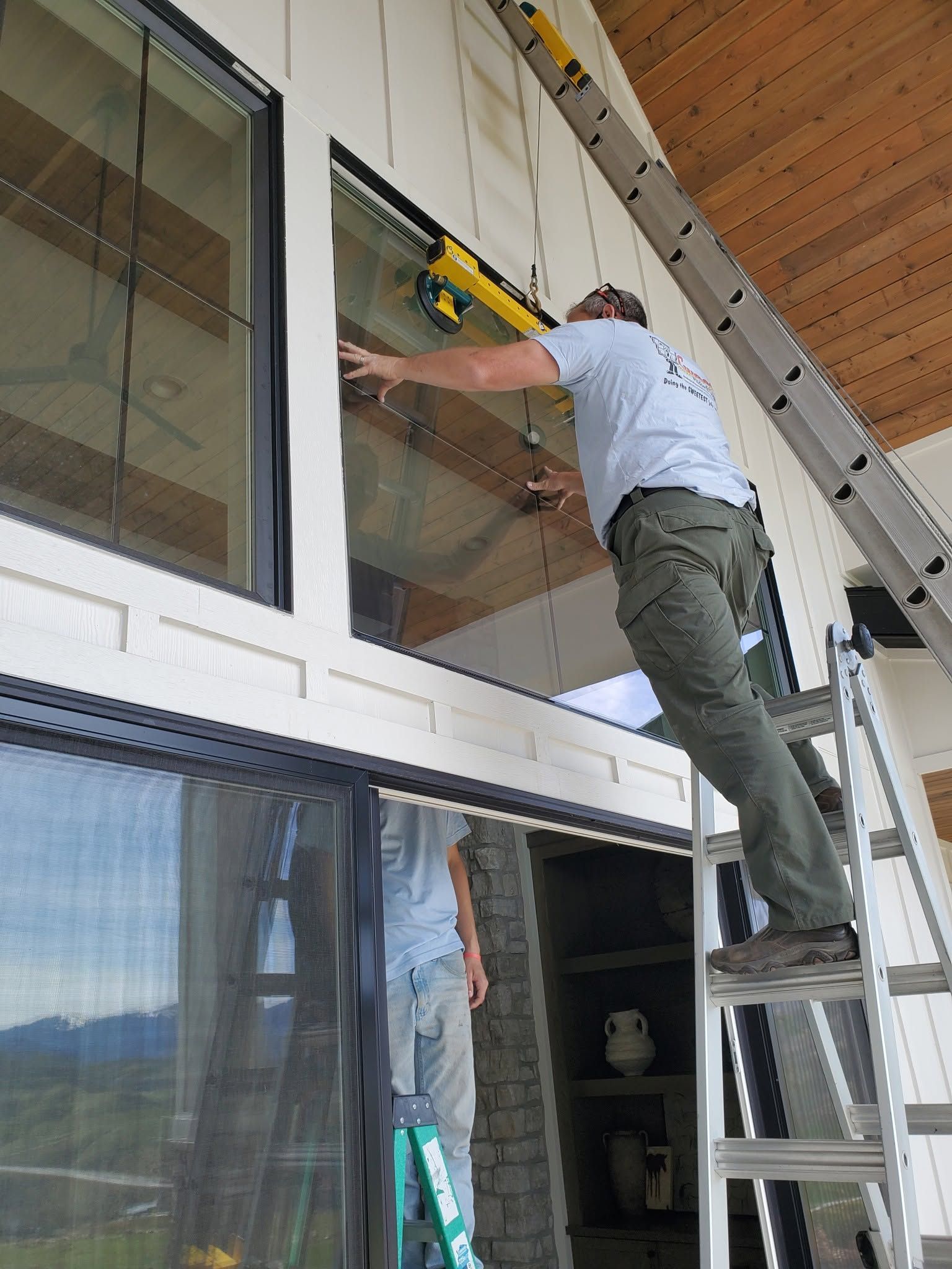 Worker on a ladder installing or adjusting a window on a building exterior