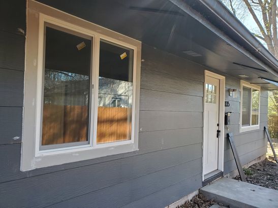Gray house exterior with white-trimmed windows and a front door under a sloped roofline