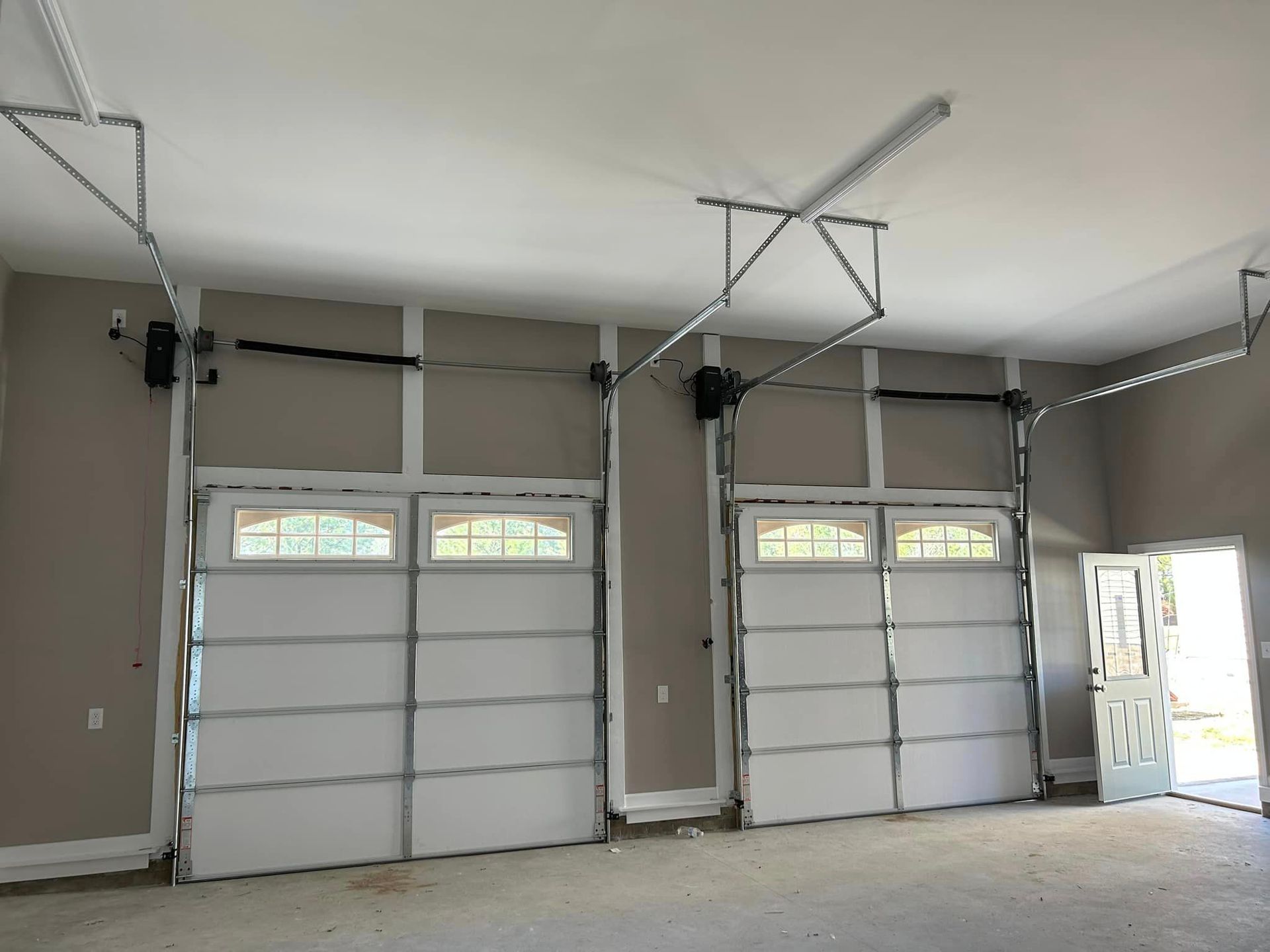 A garage with two garage doors open and a door open.