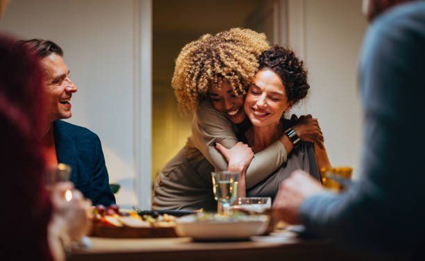 Two women hugging at a dinner table