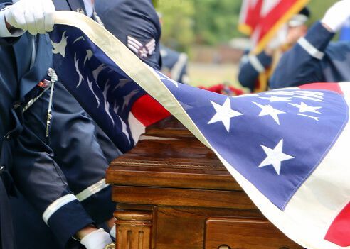 A flag being laid over a casket