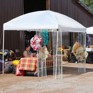 A woman is sitting at a table under a white tent.