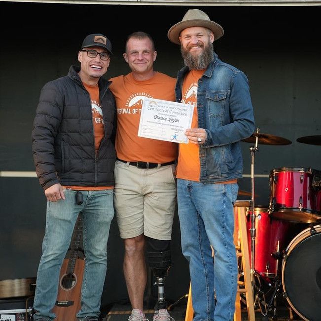 A man with a prosthetic leg is holding a certificate