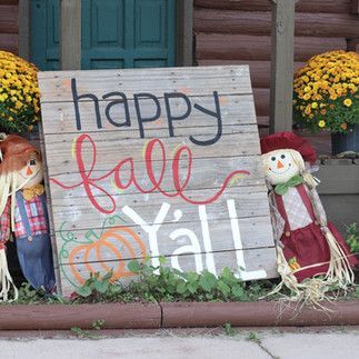 A wooden sign that says `` happy fall y'all '' is sitting on a porch.