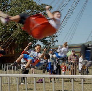 A group of people are riding swings at a carnival.