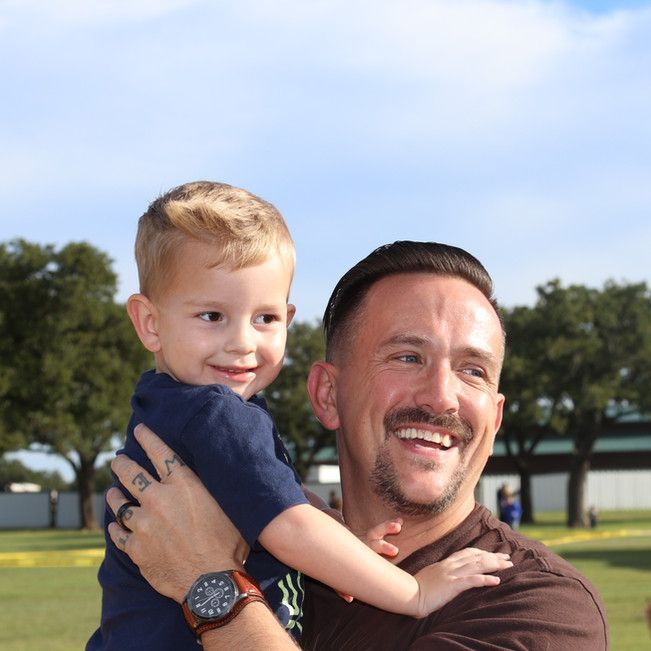 A man is holding a small child in his arms and smiling.