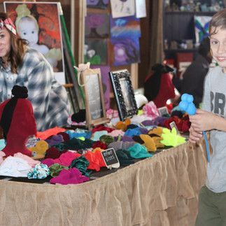 A boy is standing in front of a table filled with lots of colorful items.