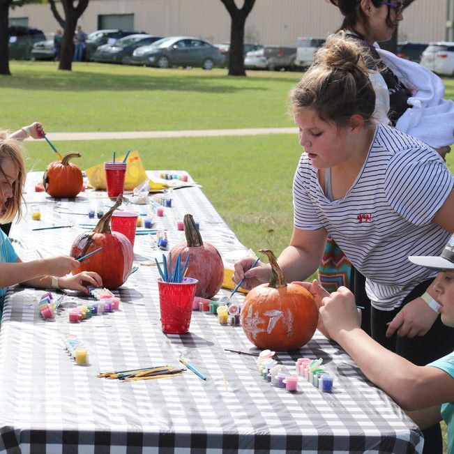 A group of children are carving pumpkins at a table