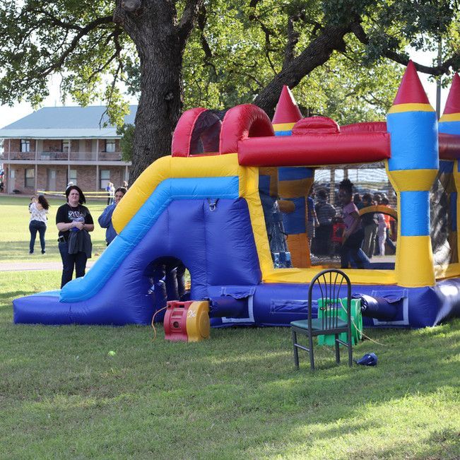 A woman stands in front of a bouncy house in a park