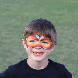 A young boy with his face painted in the shape of a butterfly.