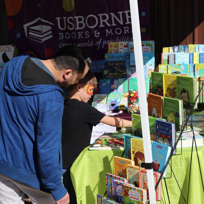 A man and child are looking at books at usborne books & more