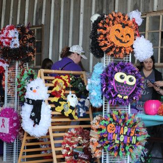 A woman is standing in front of a display of halloween wreaths.