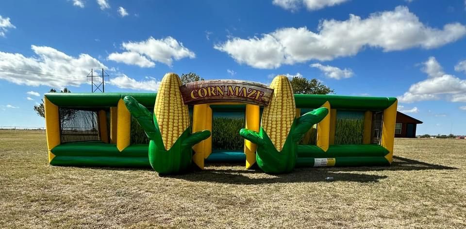 A large inflatable corn maze is sitting on top of a dry grass field.