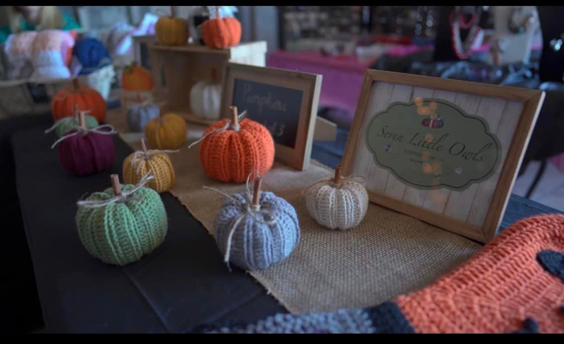 A table with a bunch of crocheted pumpkins on it