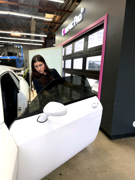 Woman leaning into a white car door inside an auto shop