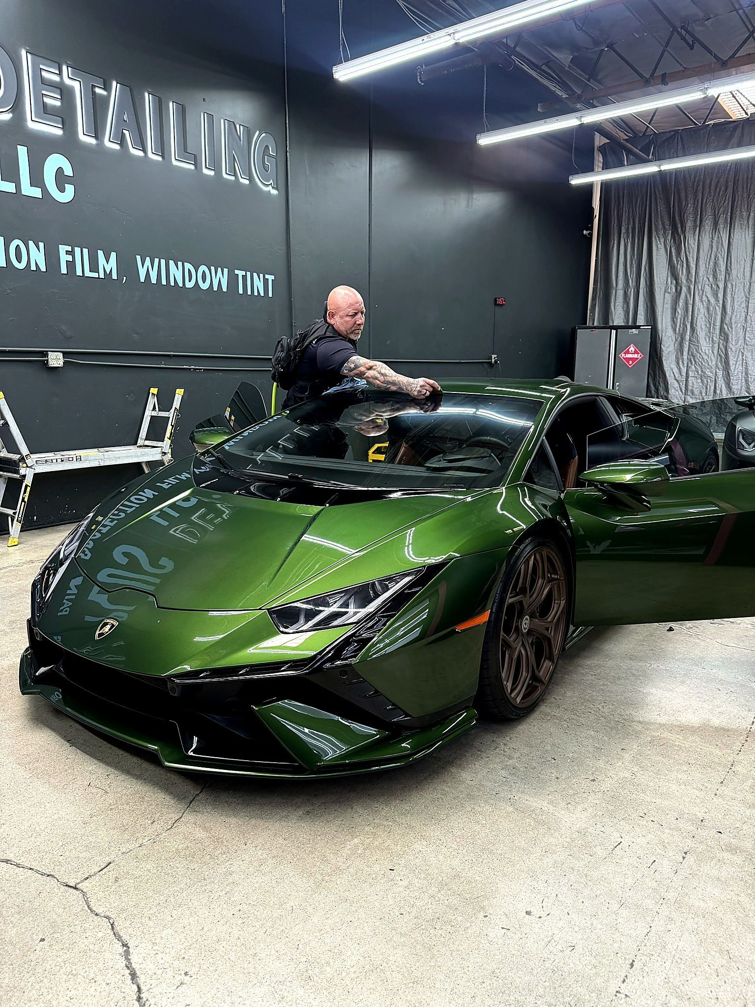 Green sports car in a garage showroom with a person leaning on it