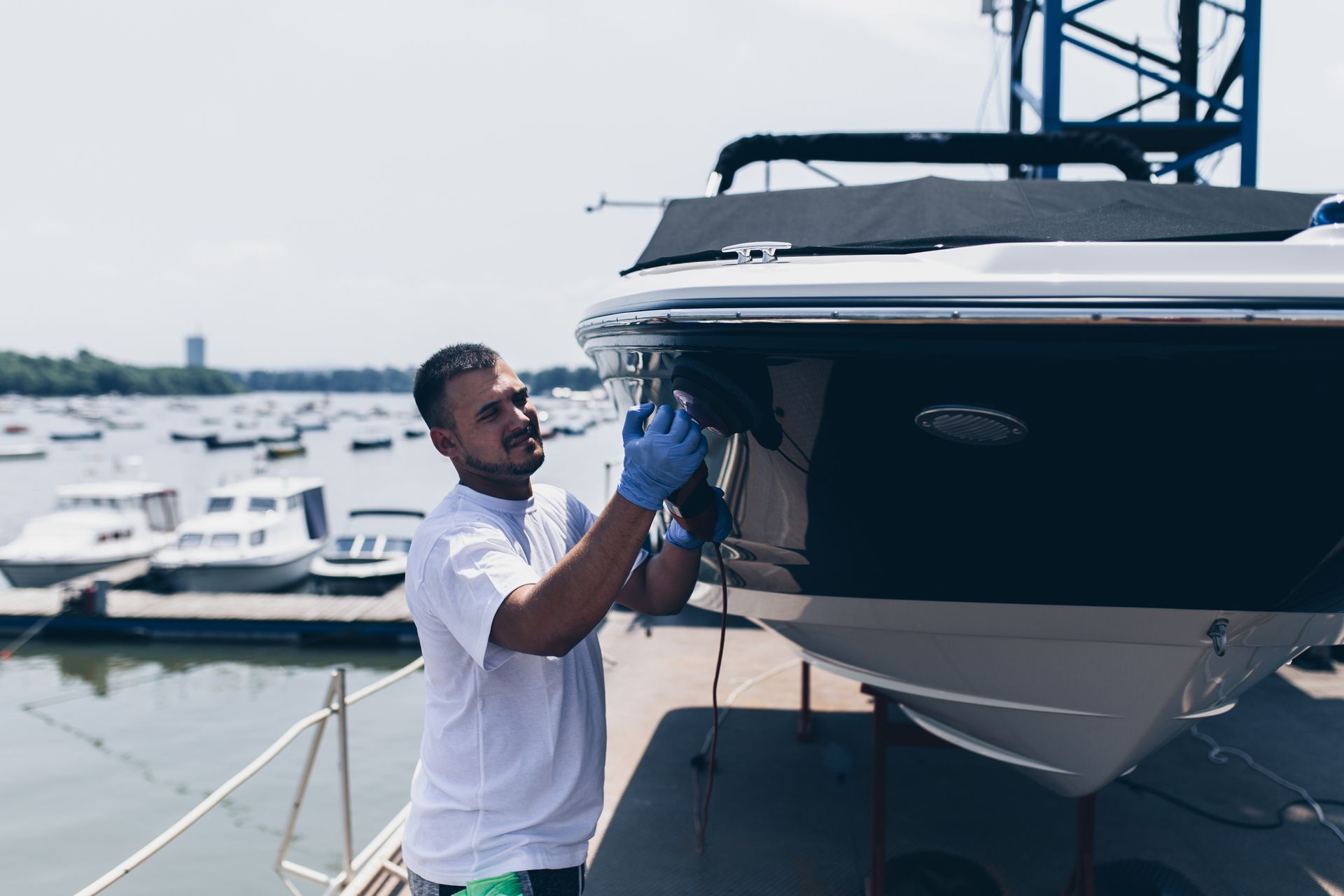 Man polishing the bow of a large white yacht at a marina