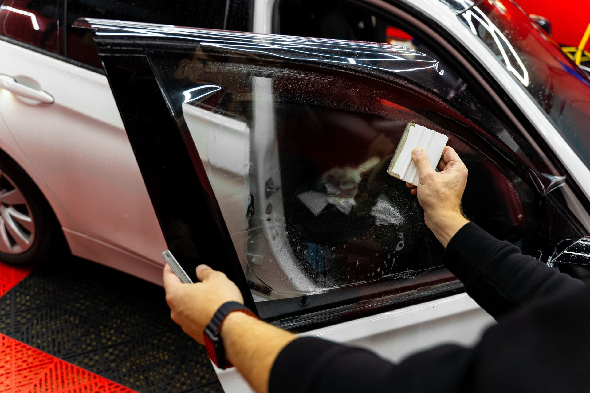 Person applying film to a car window in a workshop