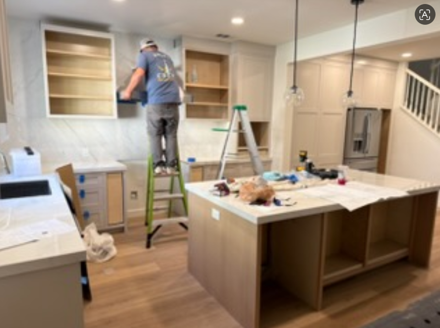 Modern kitchen with navy cabinets, white marble counters, open shelves, and warm under-cabinet lighting