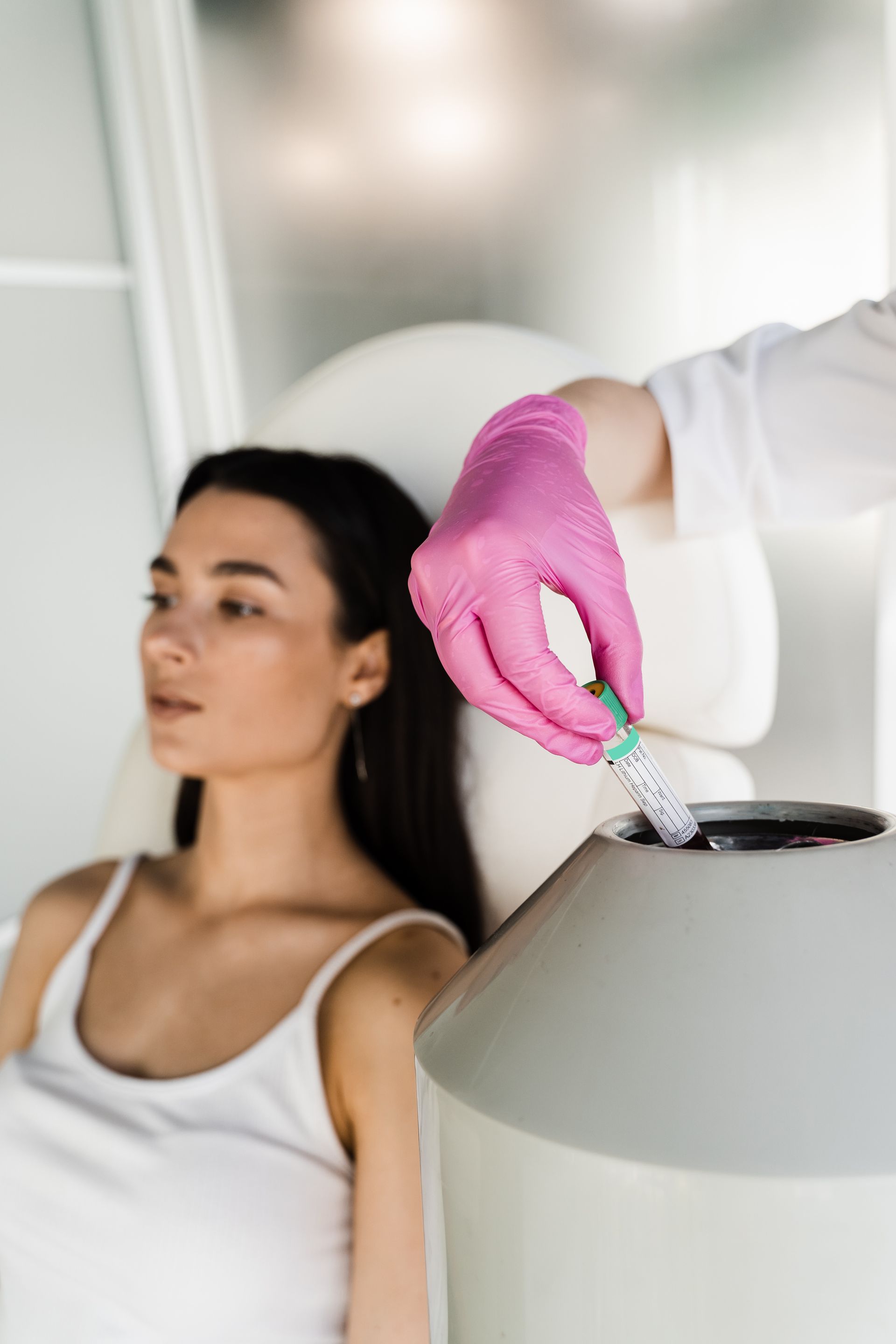 Person receiving a facial treatment. A gloved hand uses a device on the person's forehead, in a medical setting.
