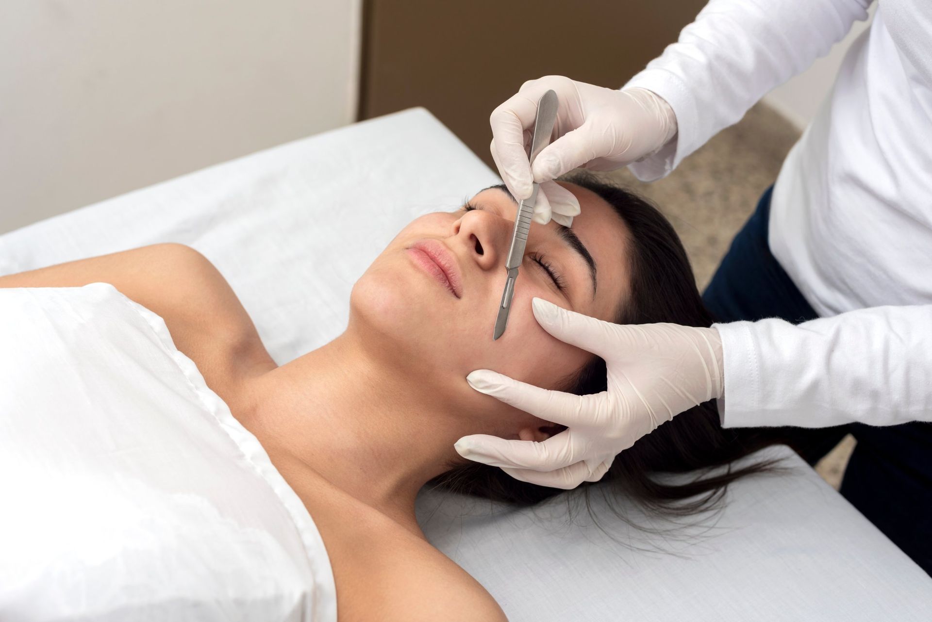 Person receiving dermaplaning facial treatment.