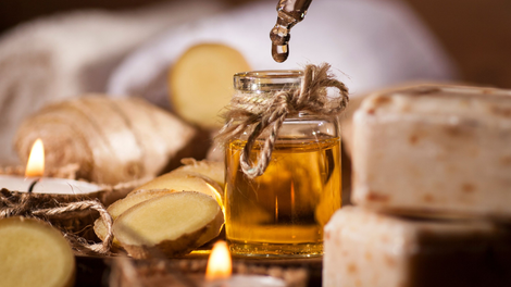 Glass bottle of honey with honeycomb, garlic, ginger and candle on a rustic table