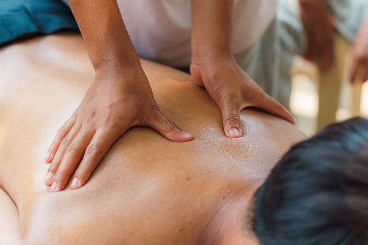 Hands giving a back massage on a person lying face down on a massage table