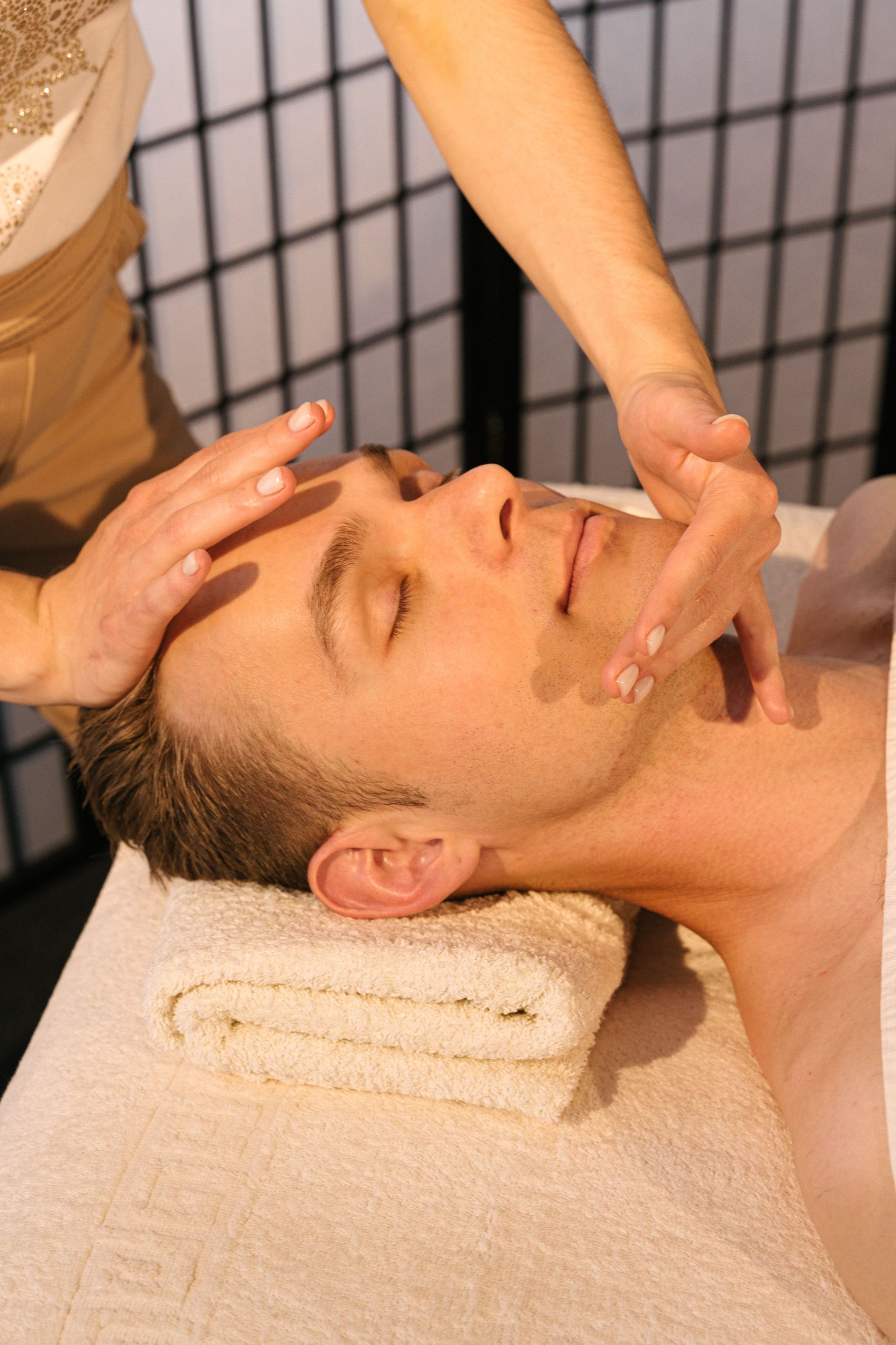 Man receiving a facial massage while reclining on a towel-covered spa table