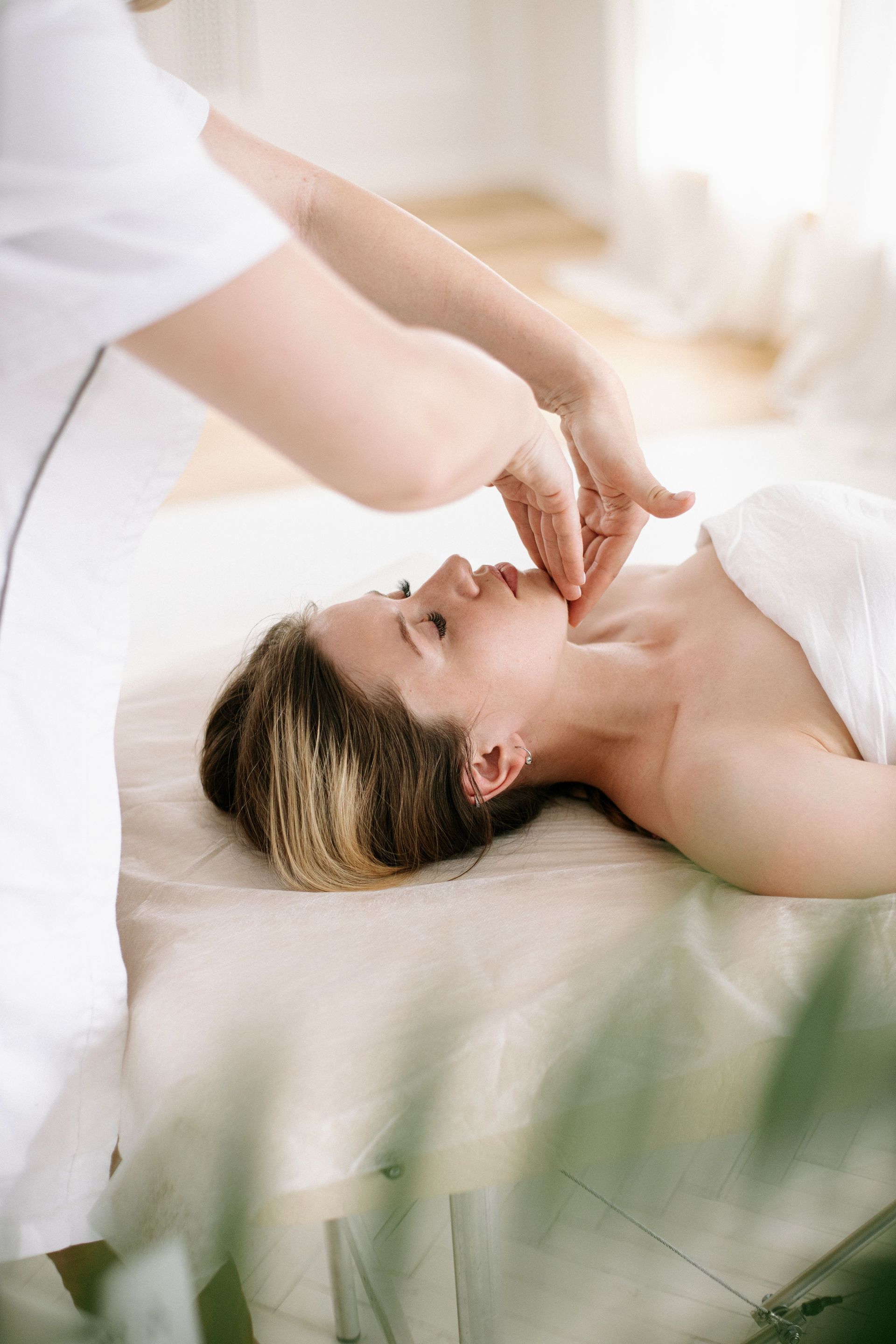 Spa therapist giving a facial massage to a client on a treatment bed