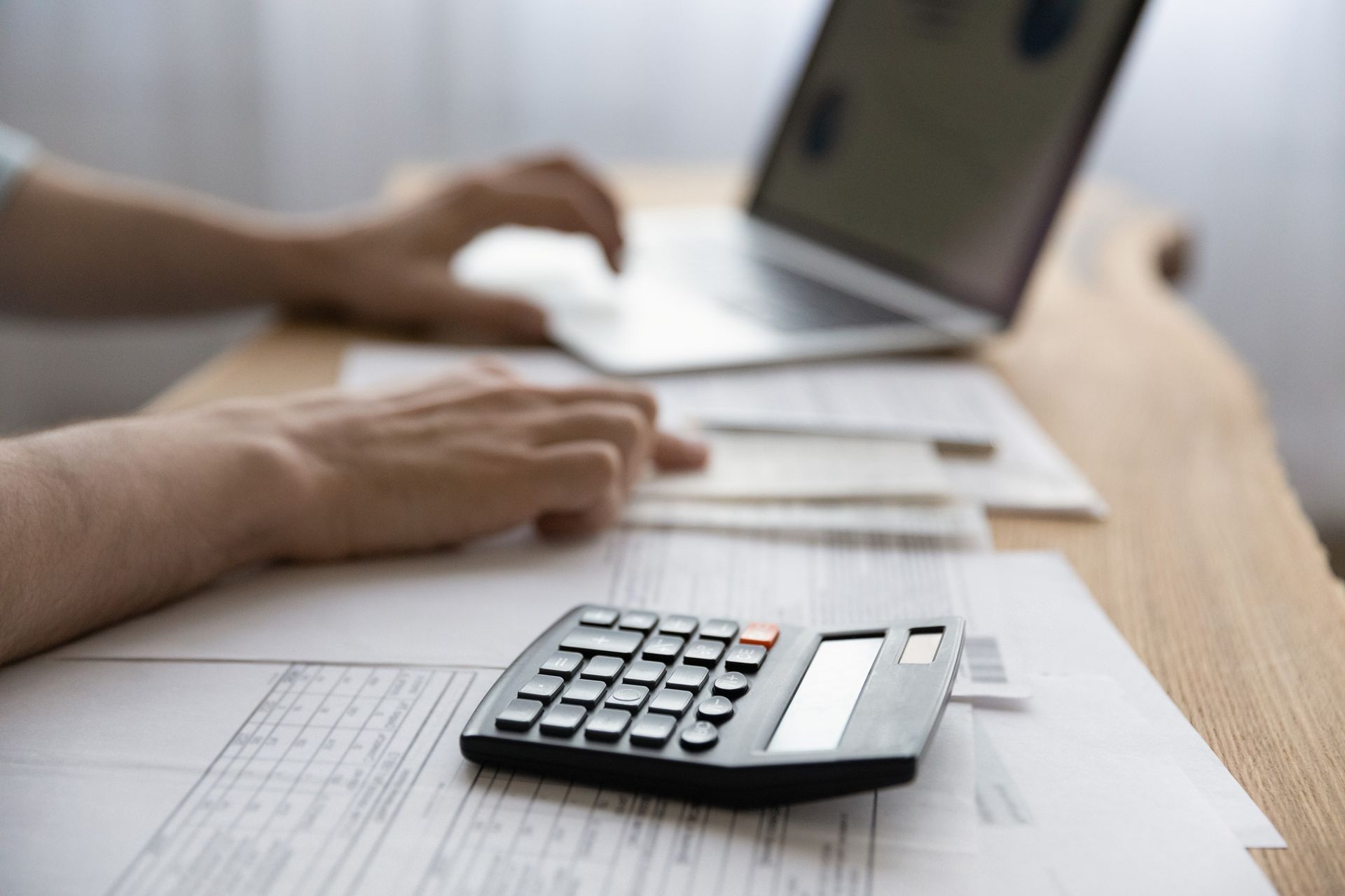 A person is using a laptop and a calculator at the same time.