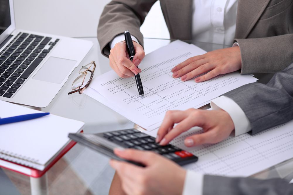 A man is using a calculator and a woman is writing on a piece of paper