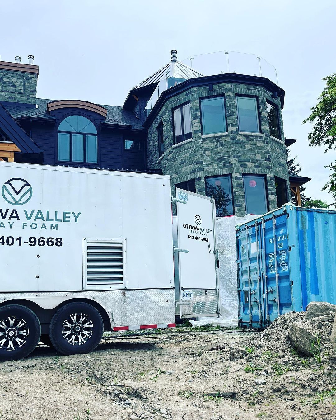 A white trailer is parked in front of a large stone building.