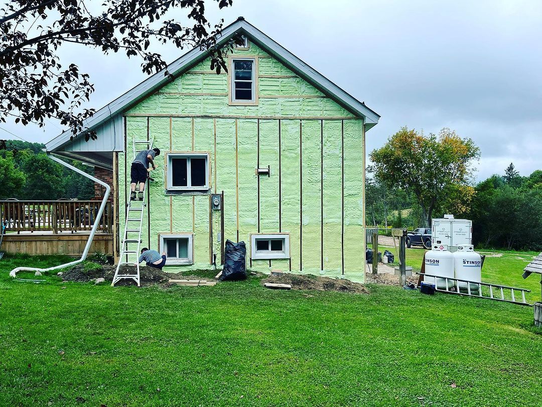 Two workers installing insulation on the facade of a green house under renovation.