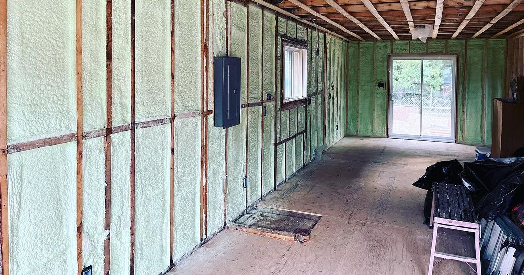 Interior of a garage under renovation with spray foam insulation on the walls.