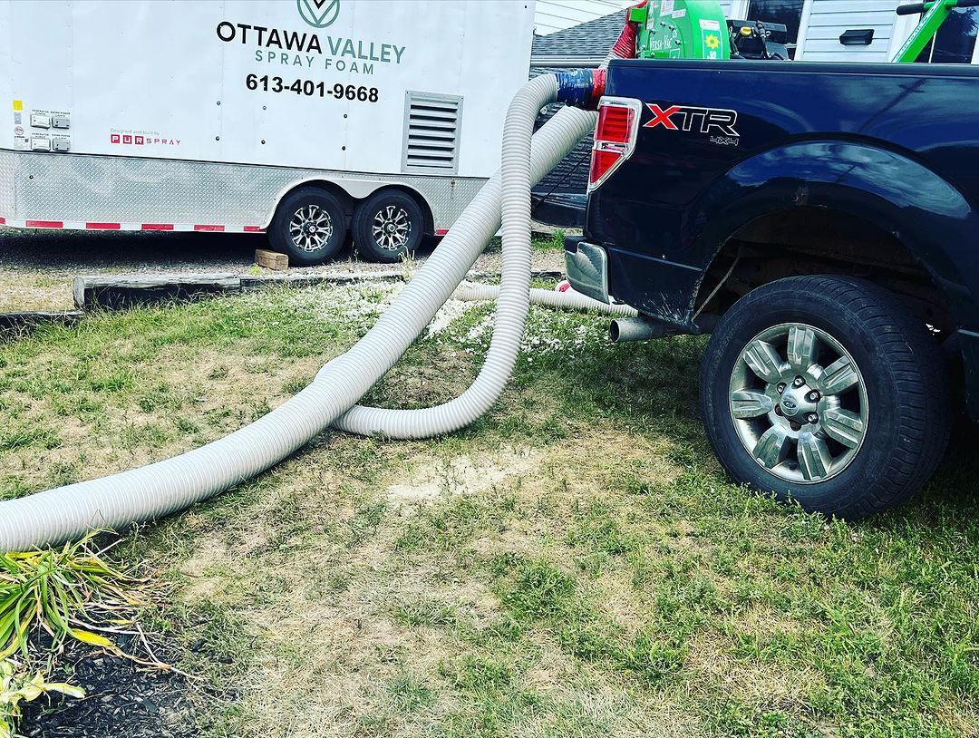 A truck is parked next to a trailer with a hose attached to it.