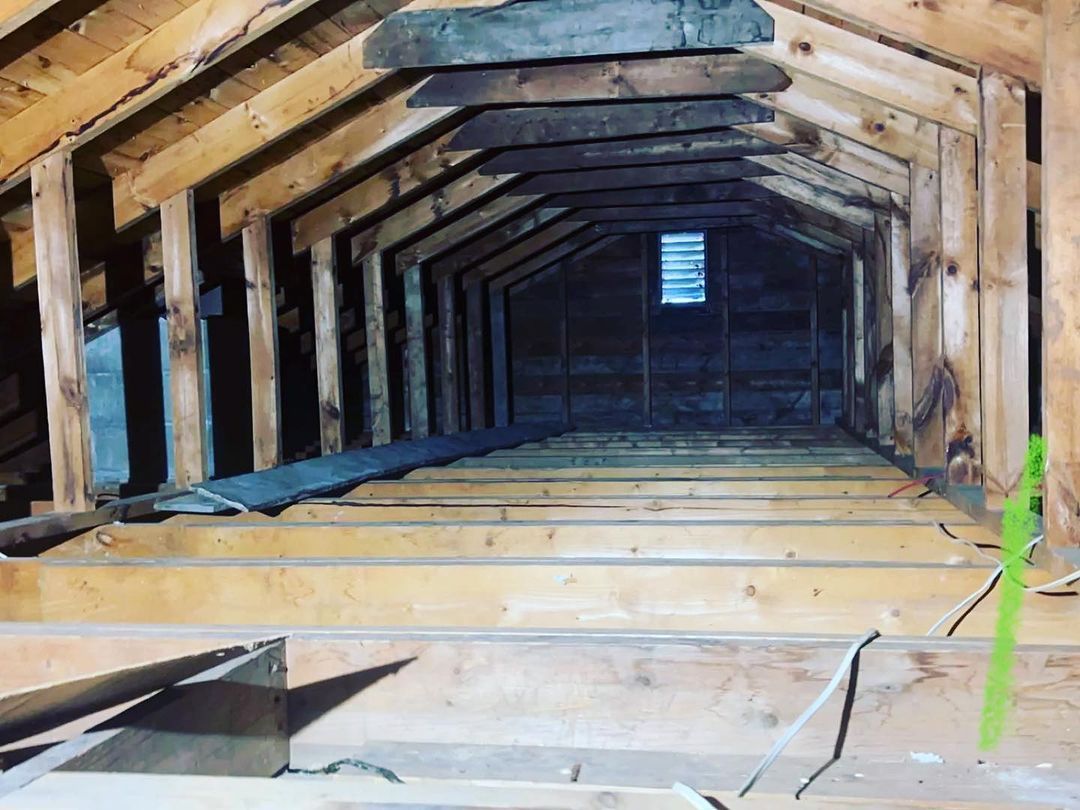 The inside of an attic with wooden beams and a window.