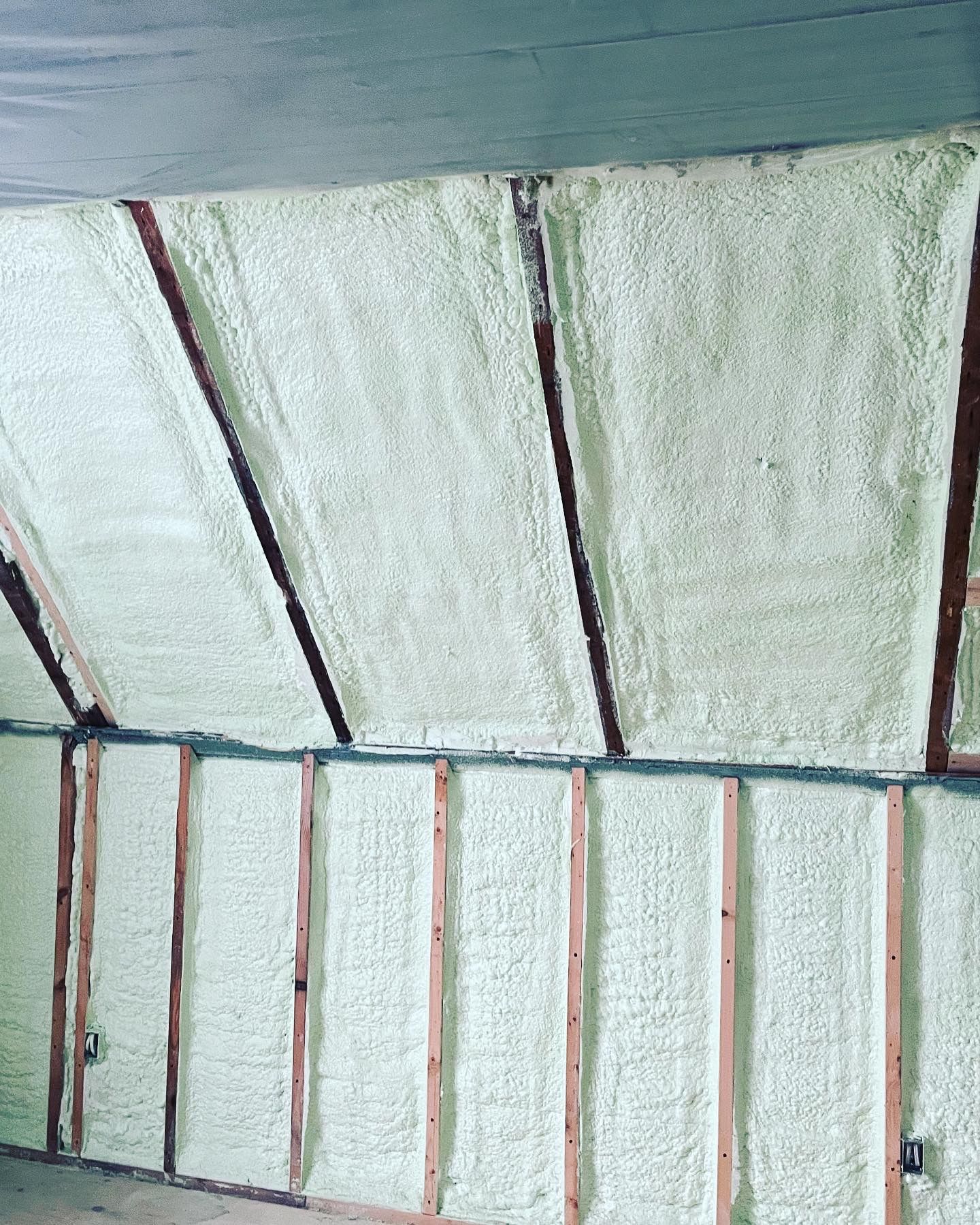 White insulation panels held by red metal studs on a wall structure.