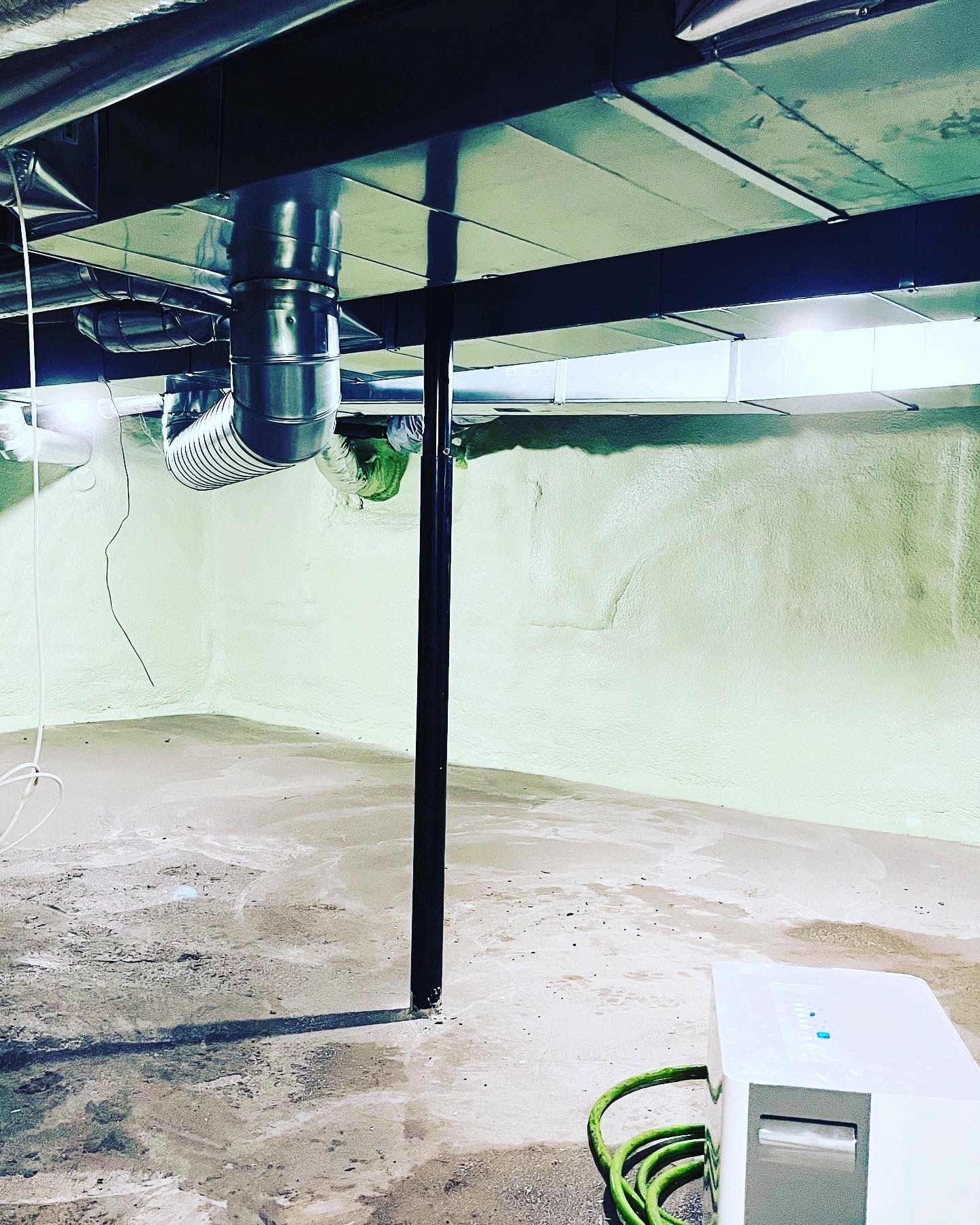 An empty basement with a hose hanging from the ceiling