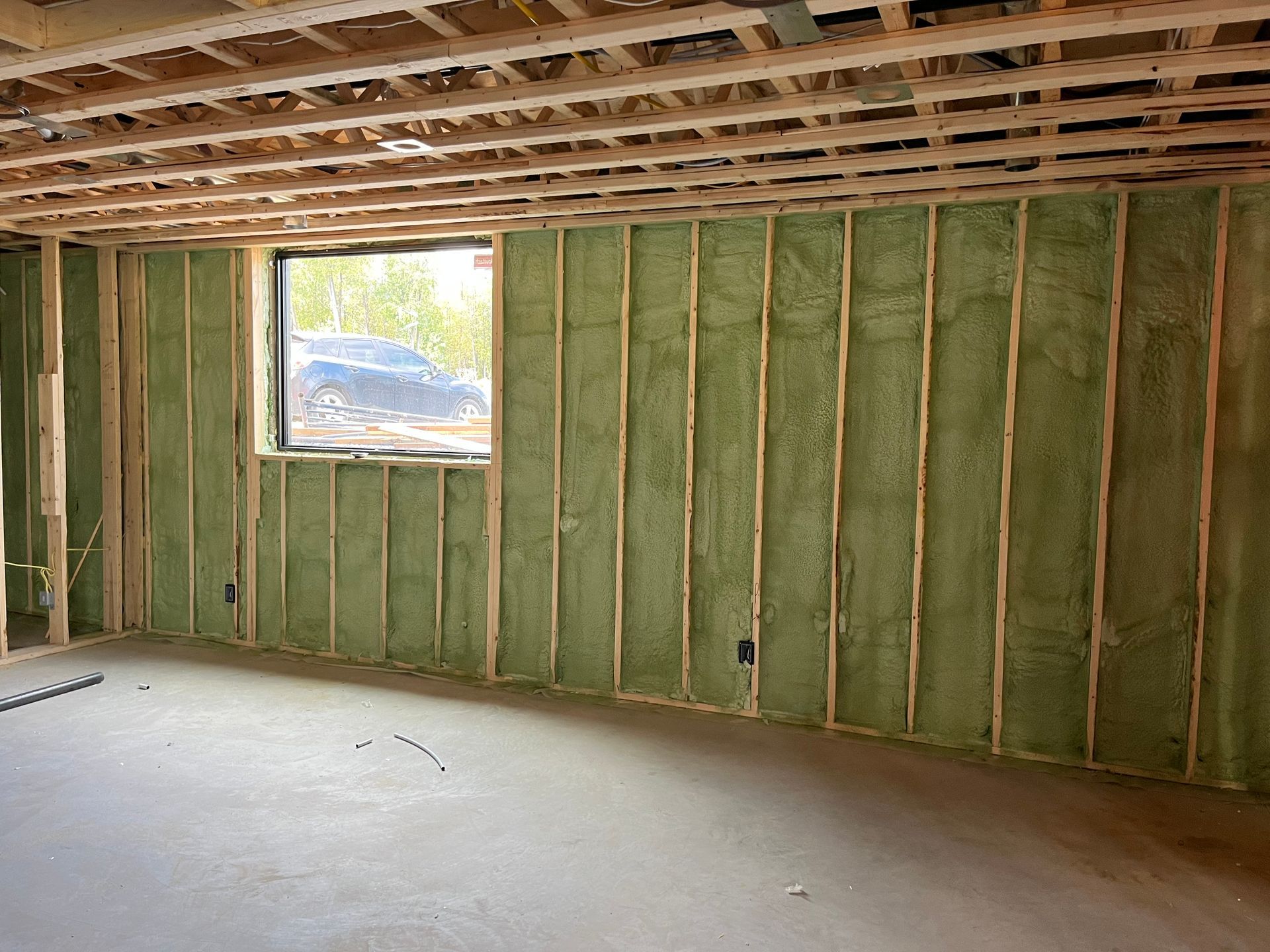 A room with green insulation on the walls and a window.