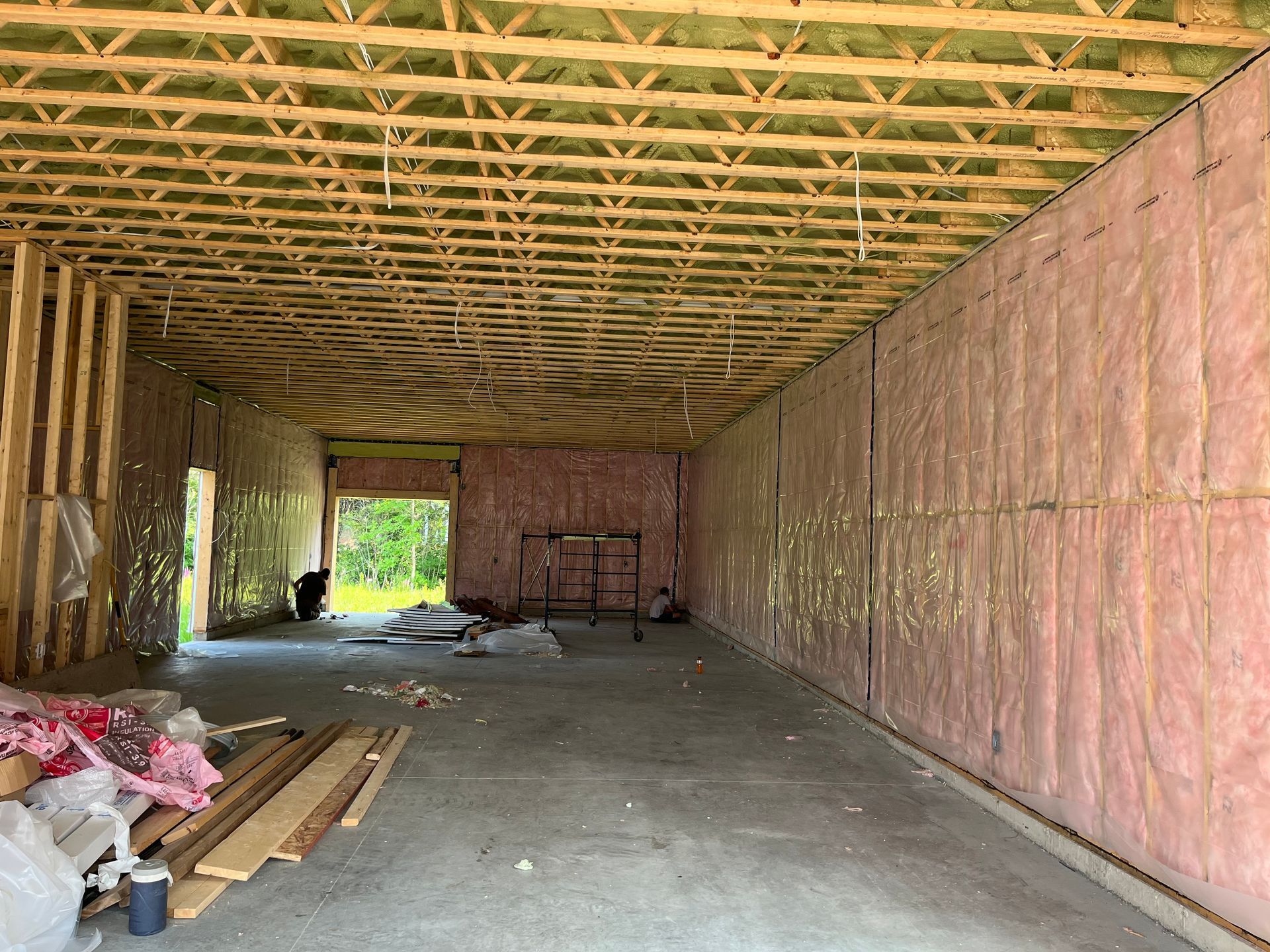 Interior of a garage under construction with wood framing and partially installed wall insulation.
