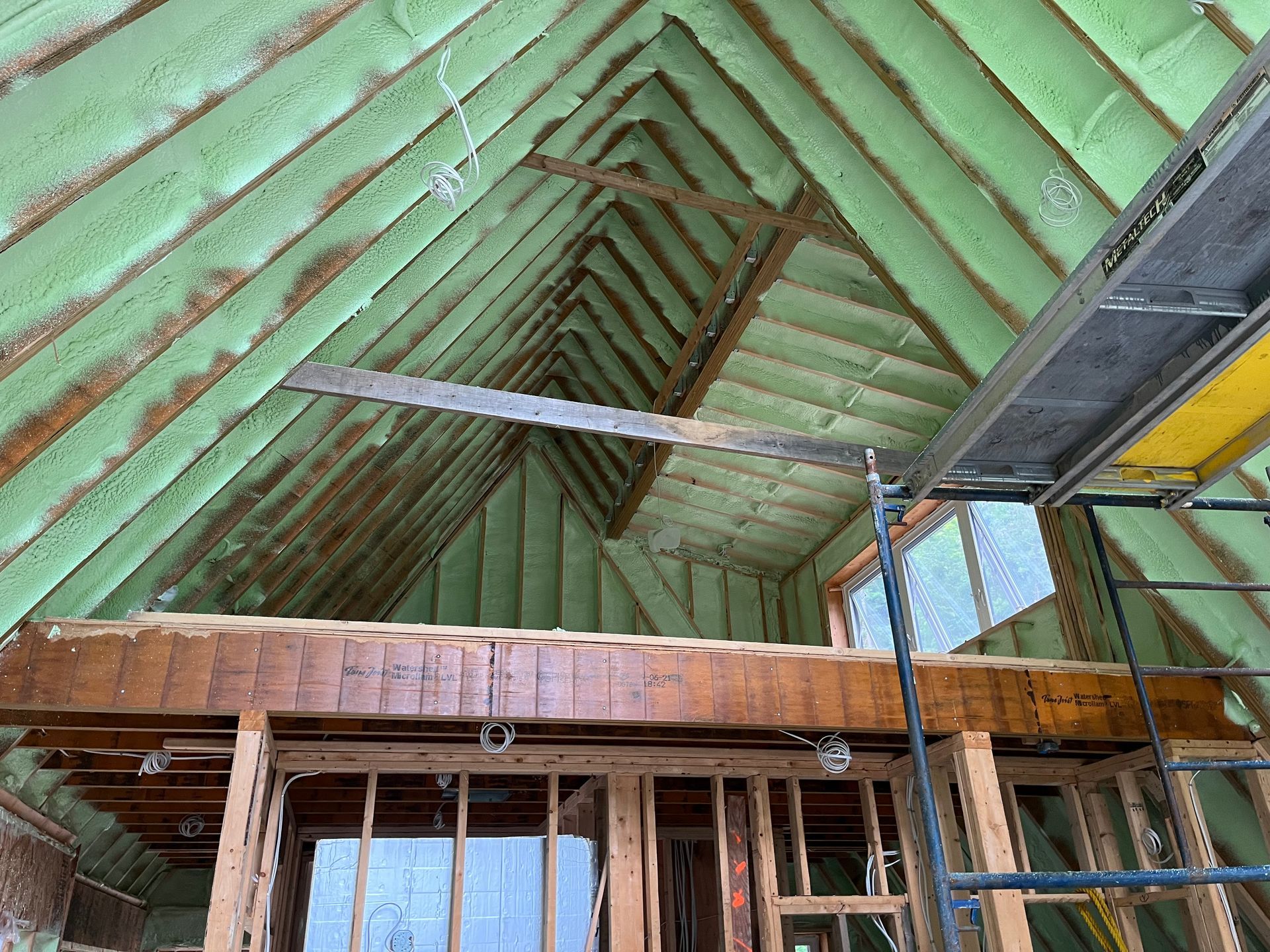 A house under construction with a green roof and scaffolding.