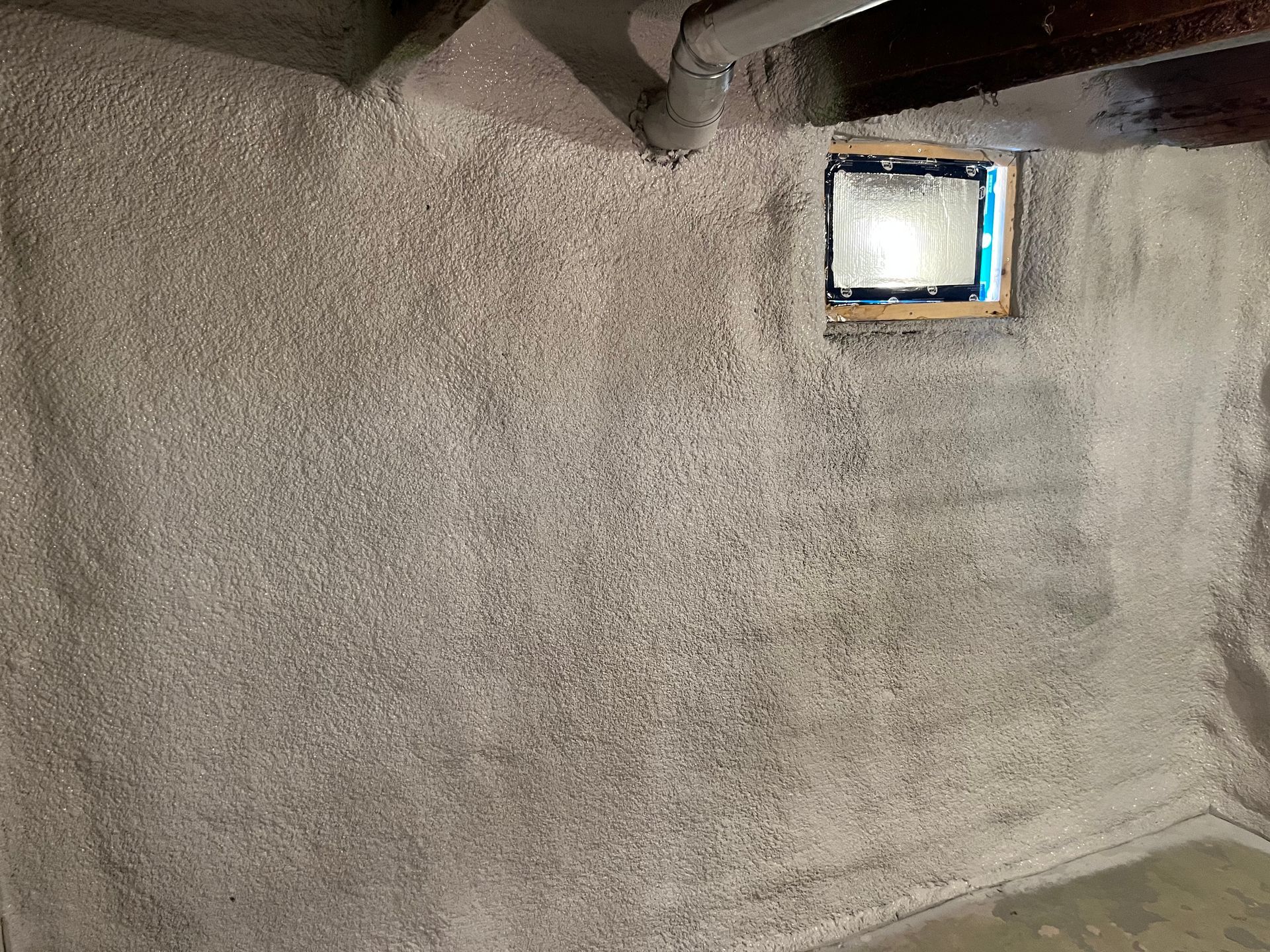 A room with a window and a light on the wall.