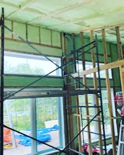 There is a scaffolding in the middle of a room with a lot of windows.
