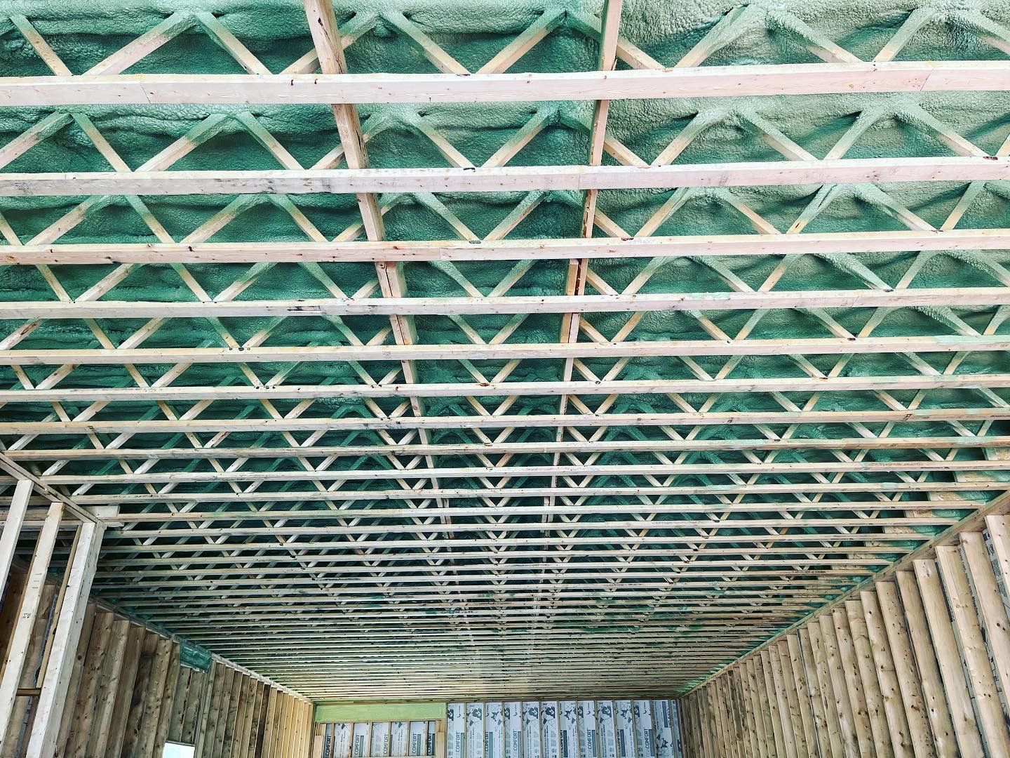 The ceiling of a building under construction with green spray foam on it.