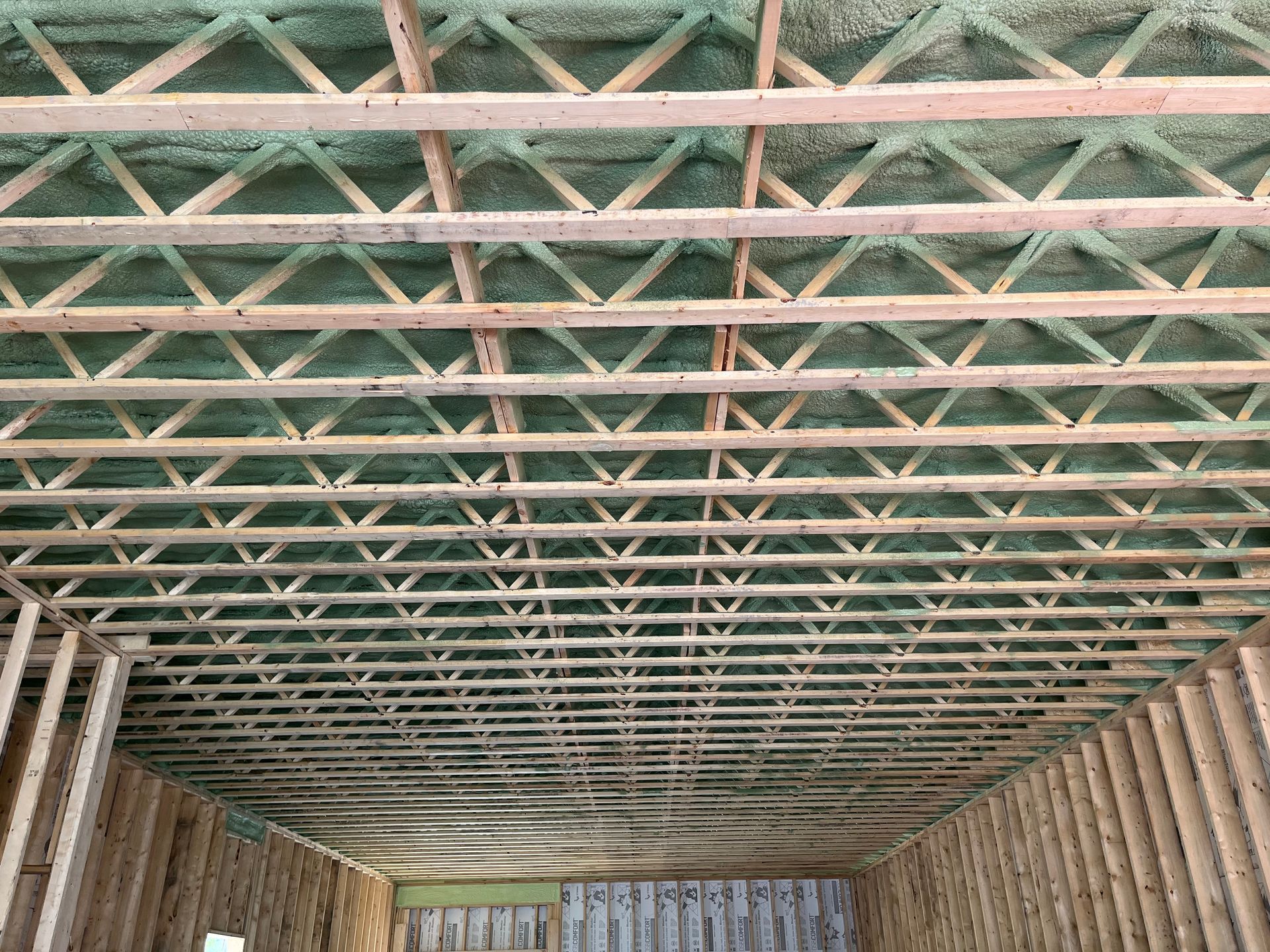 Interior view of a building structure under construction showing wood framing with crossed rafters and walls.