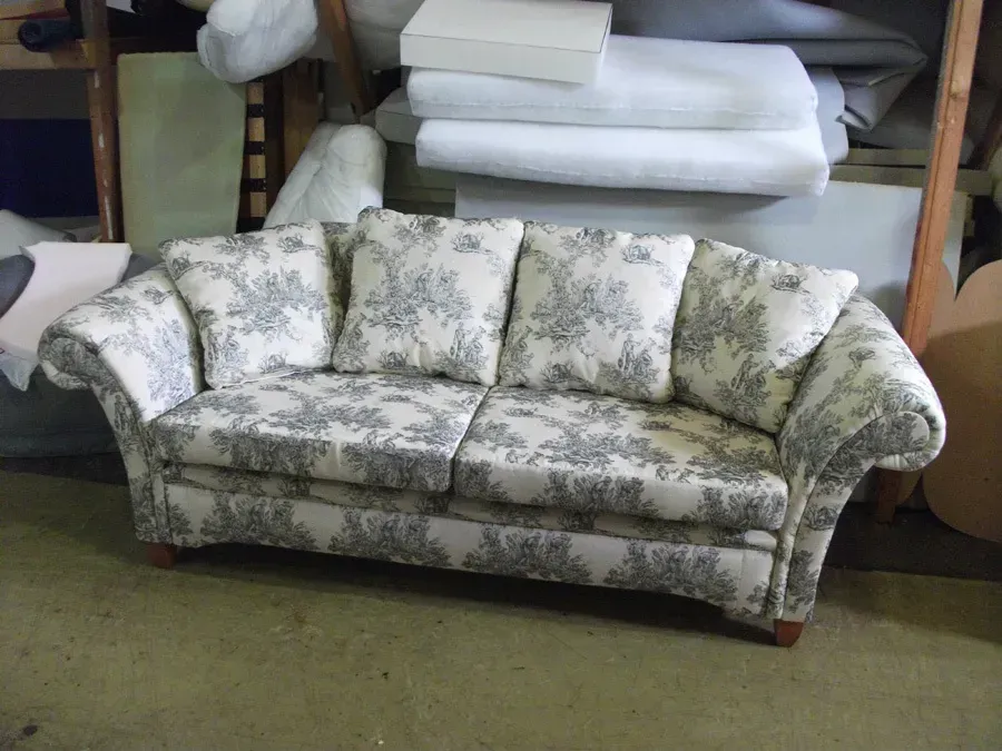 A grey and white floral couch is sitting in a room