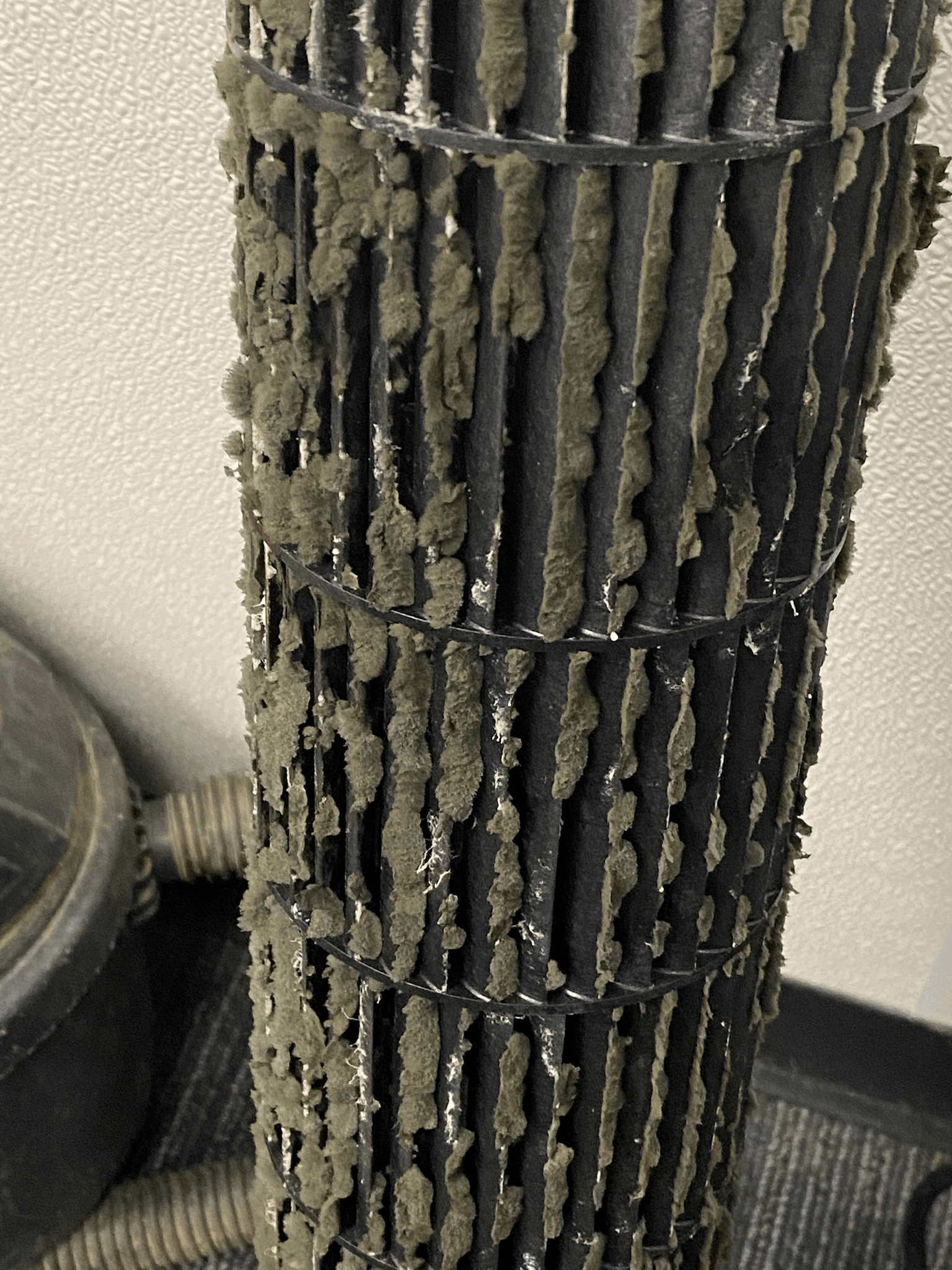 A severely dirty air filter, covered in thick clumps of dust and debris.