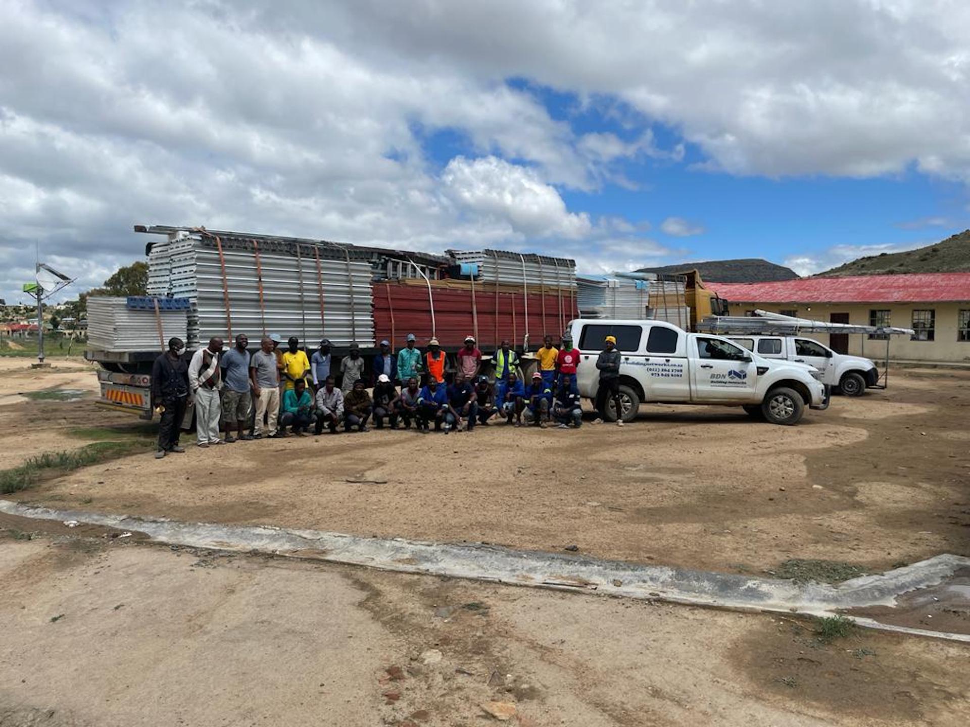 A group of people are posing for a picture in front of a truck.