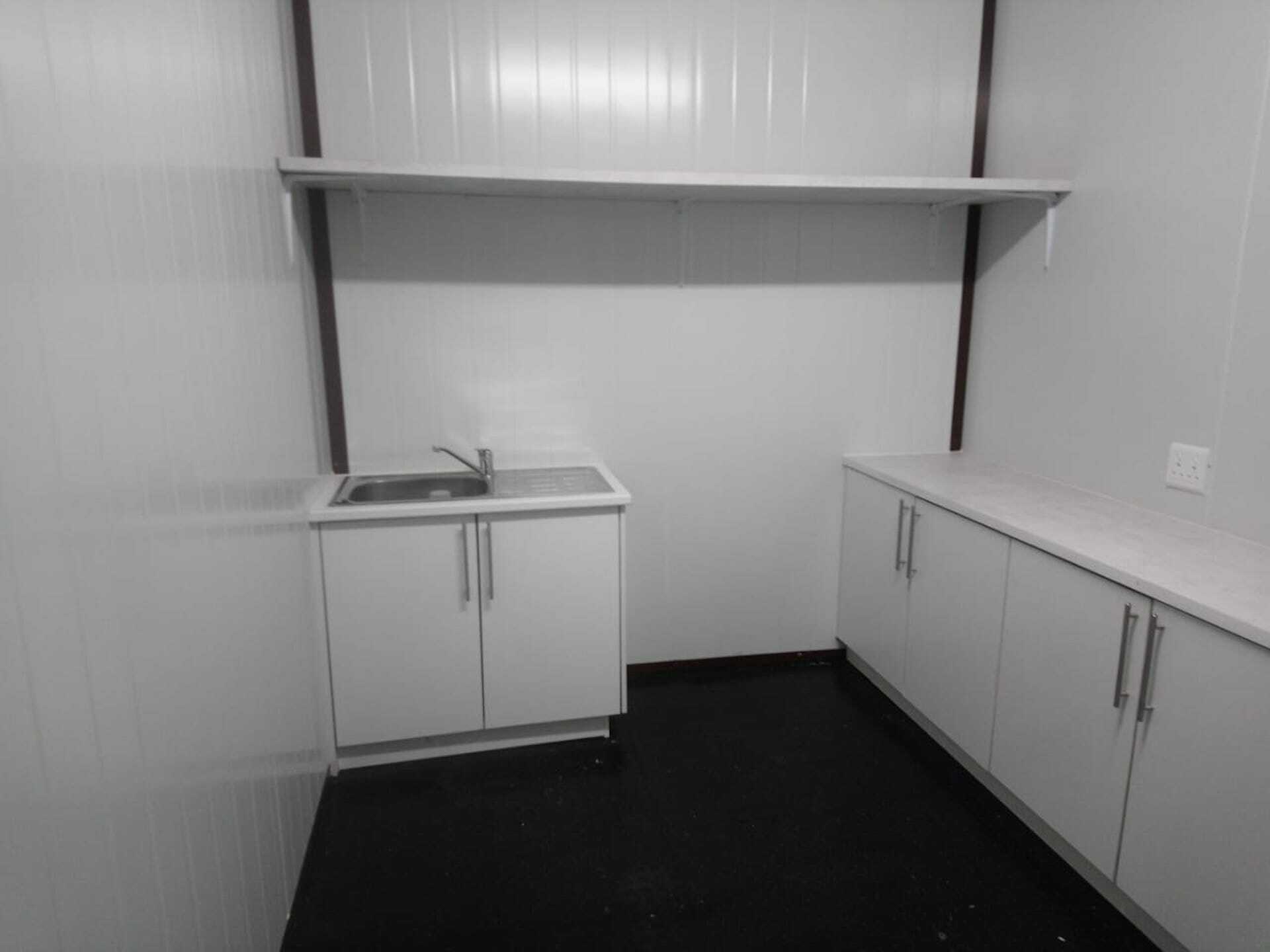 A black and white photo of a kitchen with white cabinets and a sink.